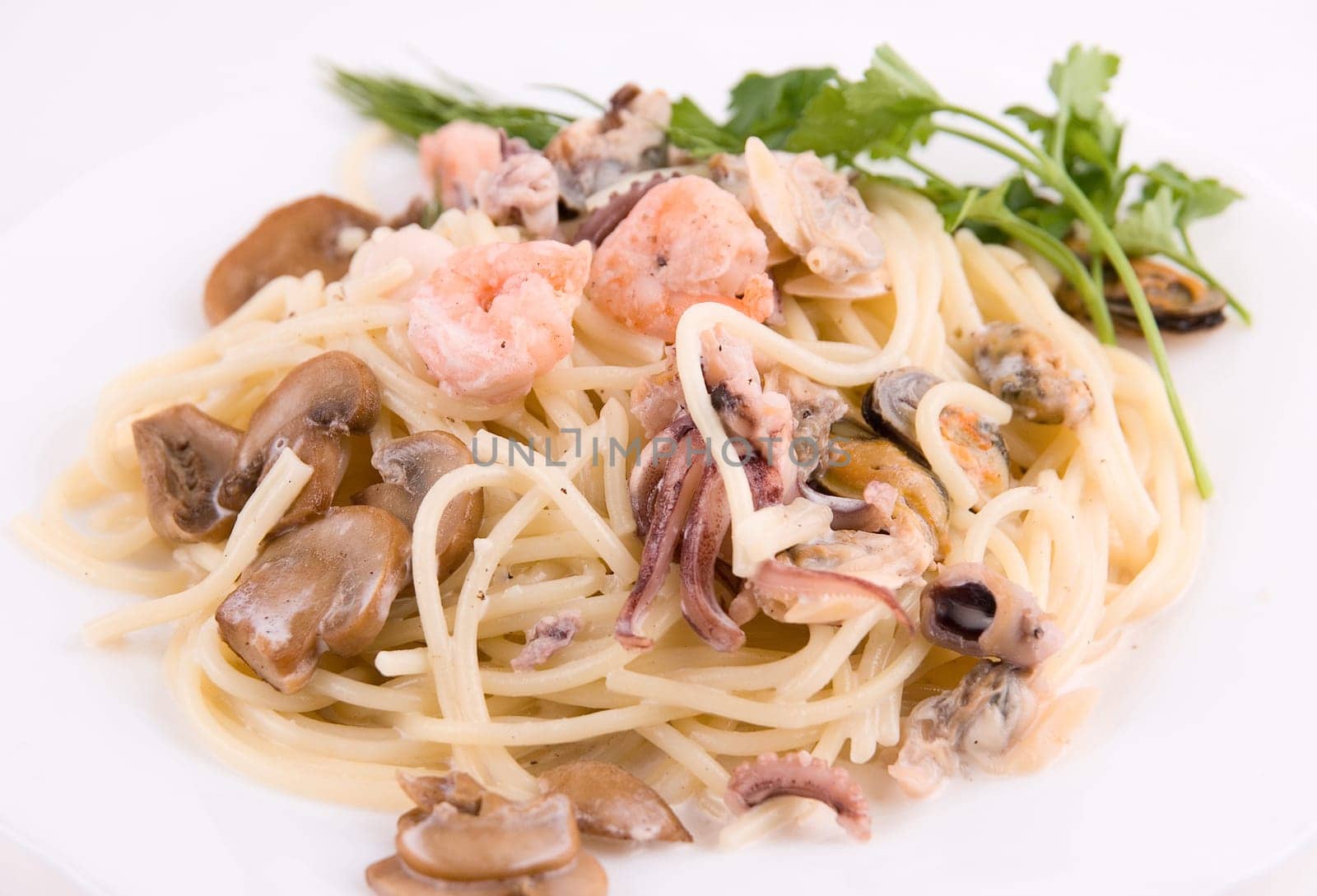 Pasta with seafood and mushrooms on white plate