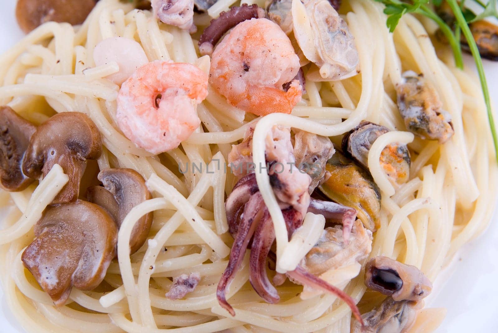 spaghetti with seafood and mushrooms on white plate