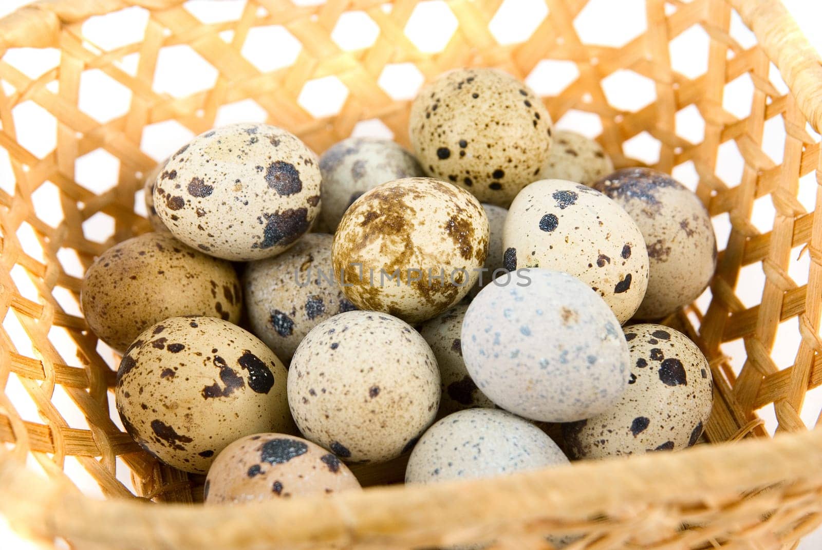 Close-up of quail eggs in the basket on white