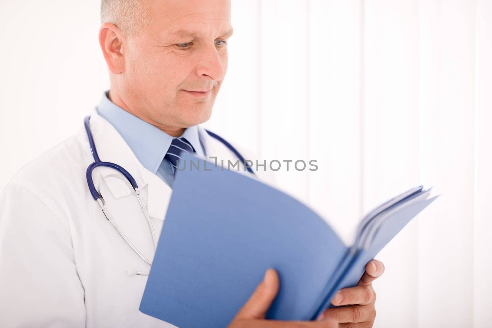 Professional senior doctor male with stethoscope look down document folders