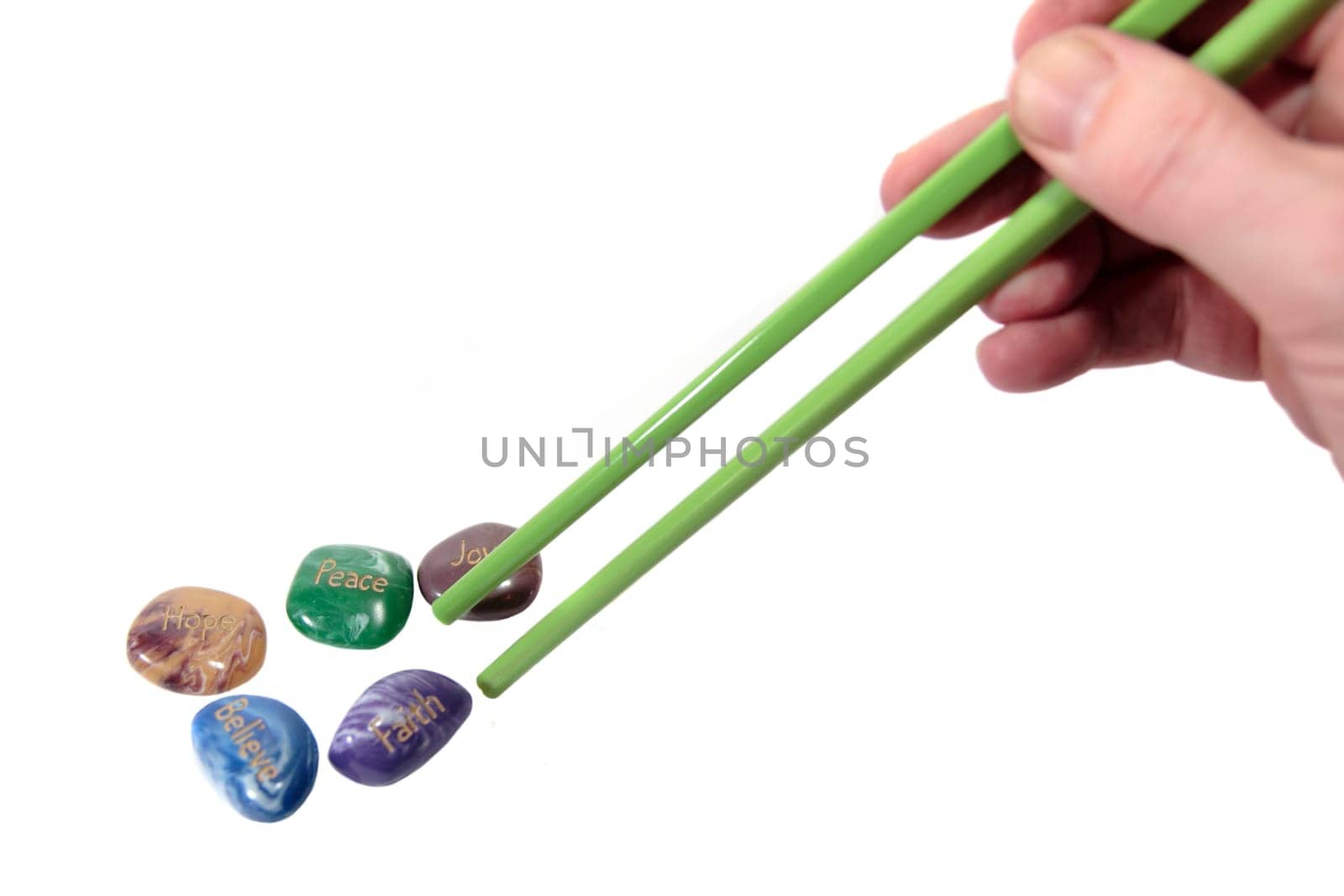 five stones inscribed hope joy peace faith and believe being picked up by chopsticks showing have belief