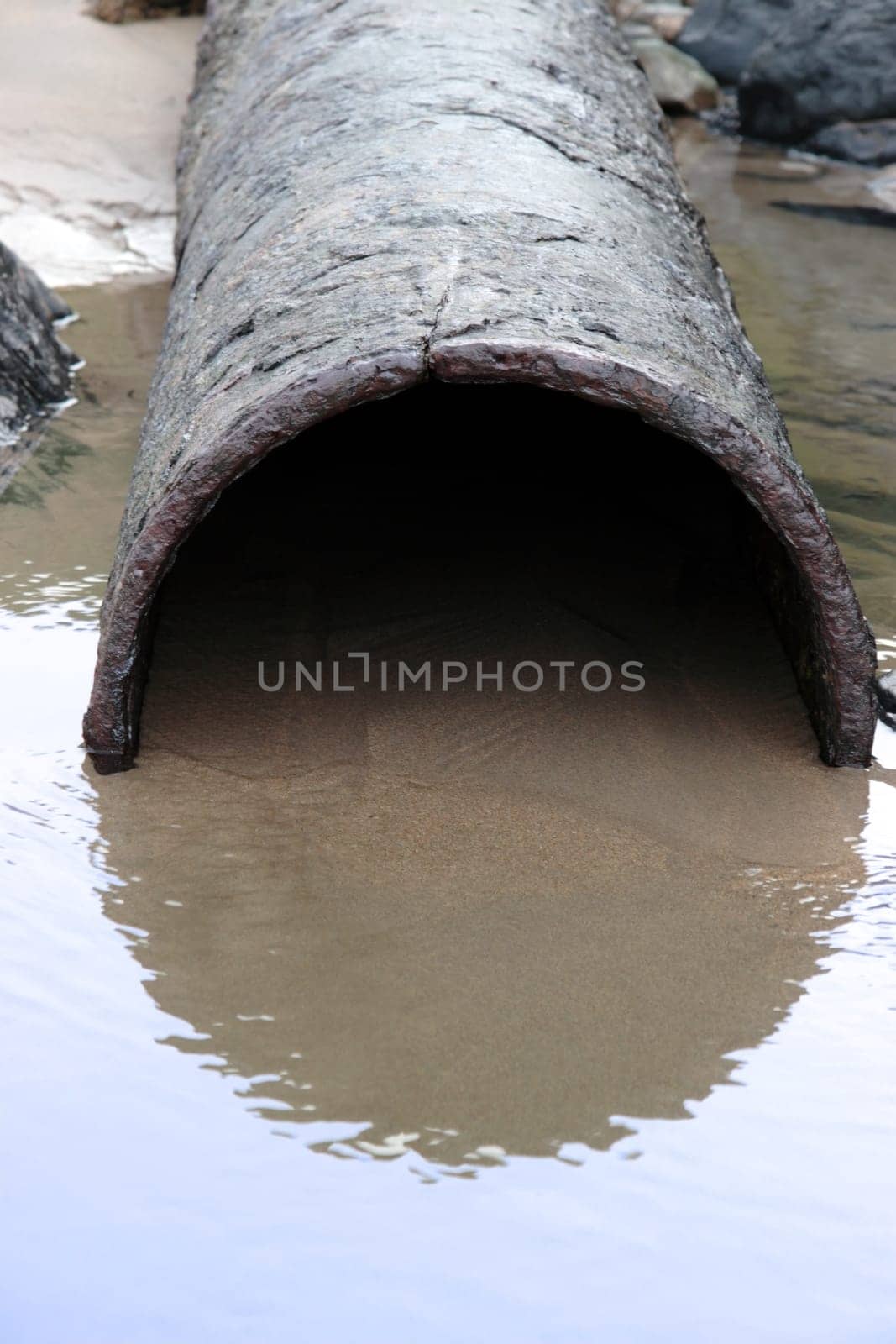 a rusty overflow pipe coming from the land to the sea