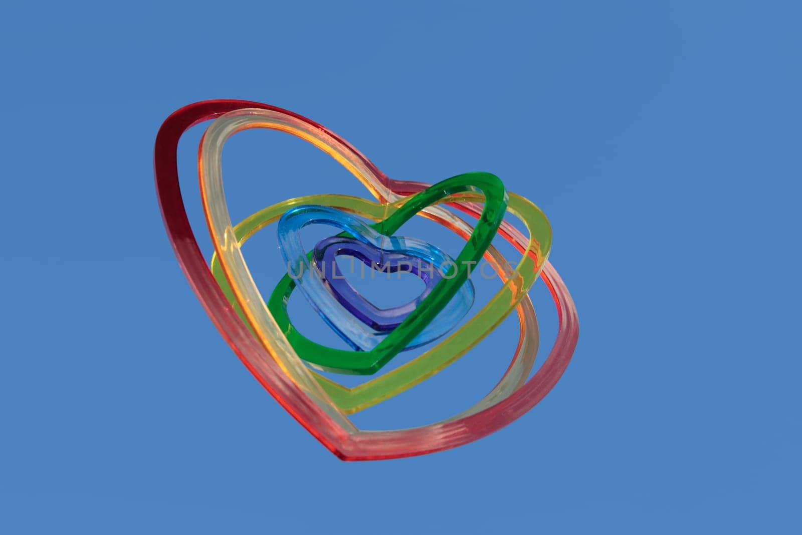six heart shaped plastic pieces one inside the other on a blue background as if floating on air