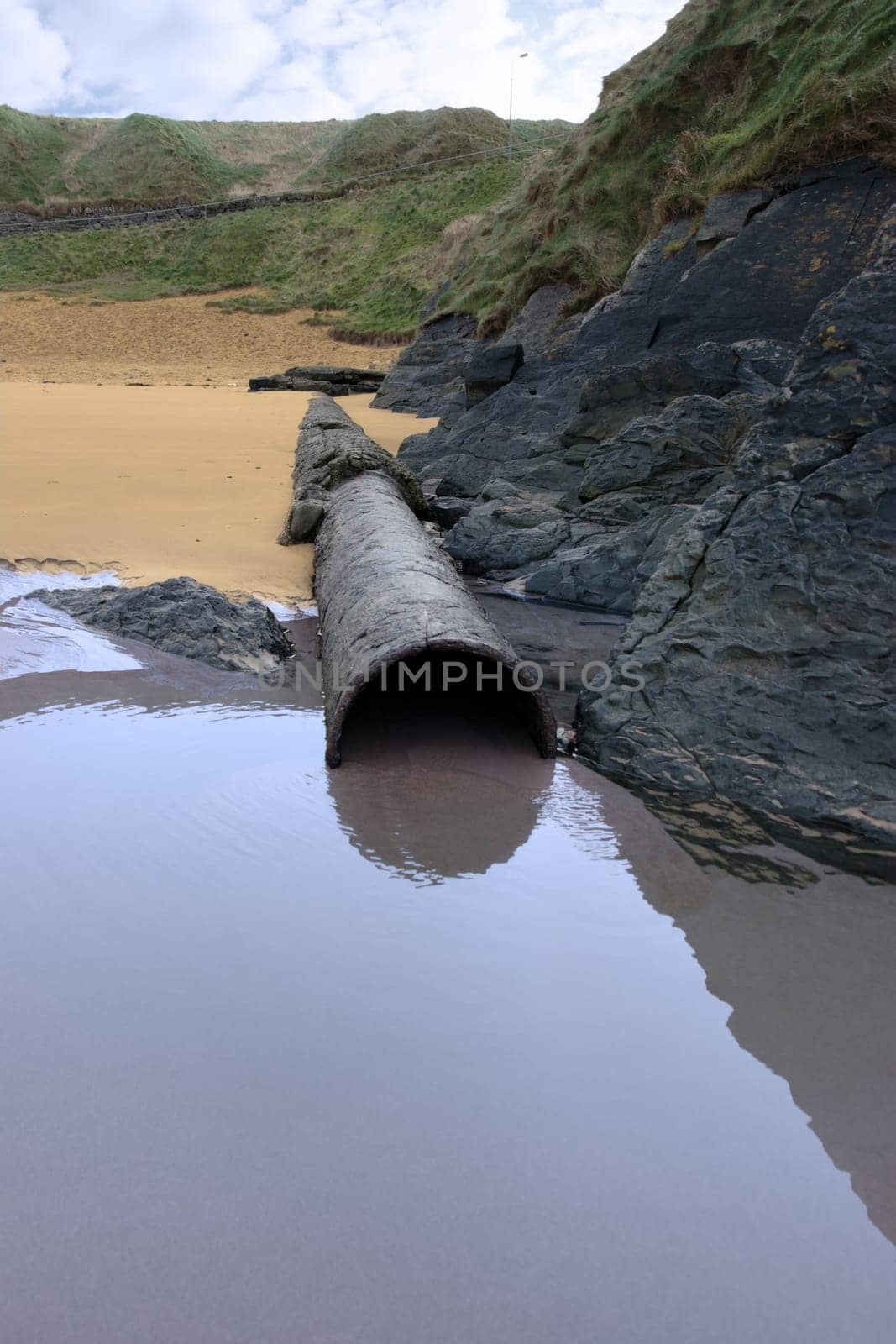 a rusty overflow pipe coming from the land to the sea
