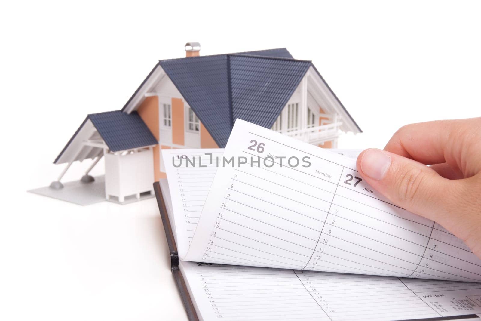 Moving house planning concept. Model of house and man browse through personal organizer.