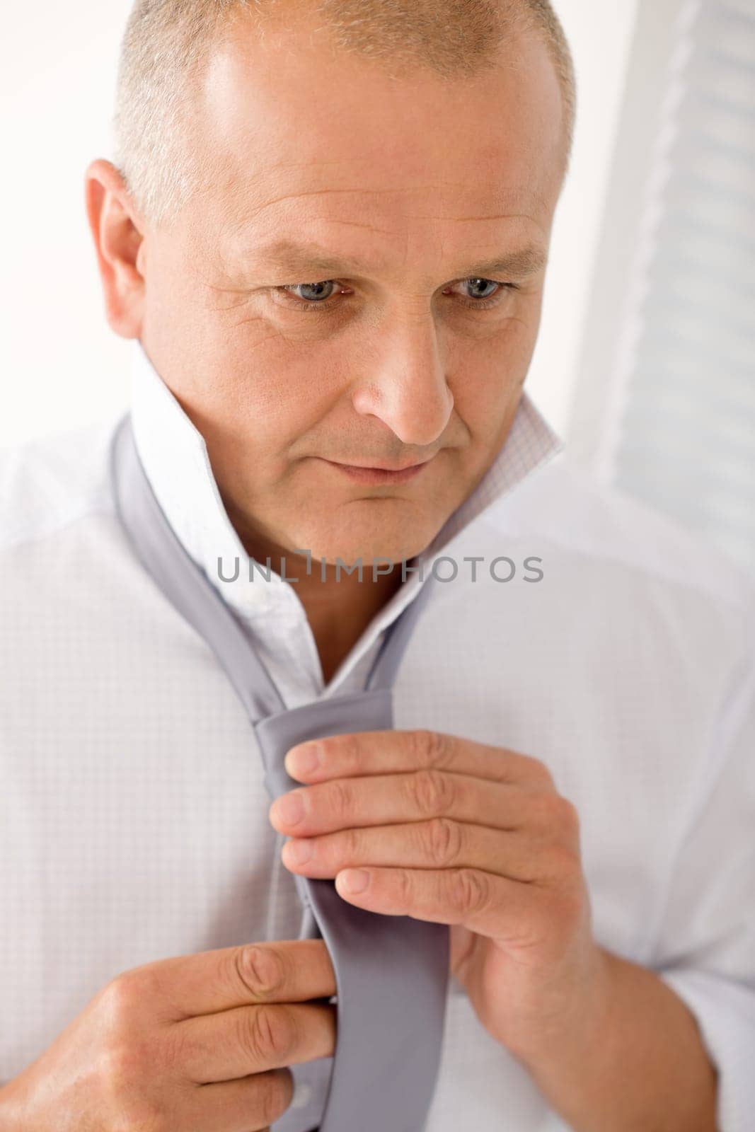 Handsome stylish mature business man tie a tie white shirt