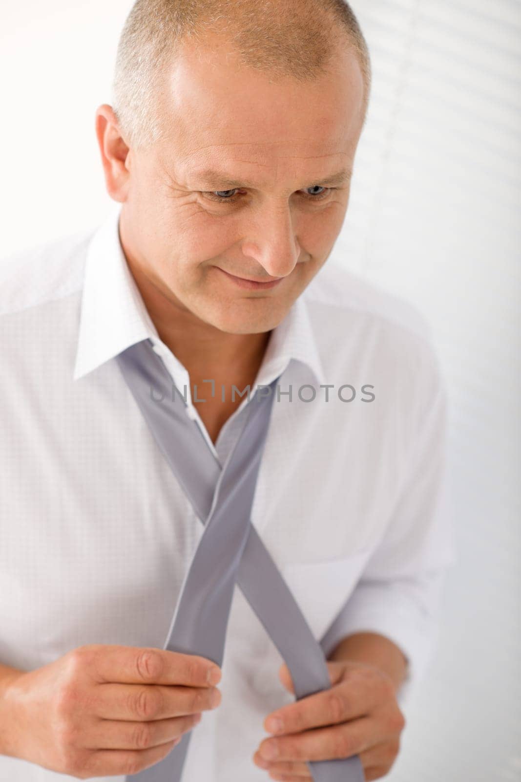 Handsome stylish mature business man tie a tie white shirt