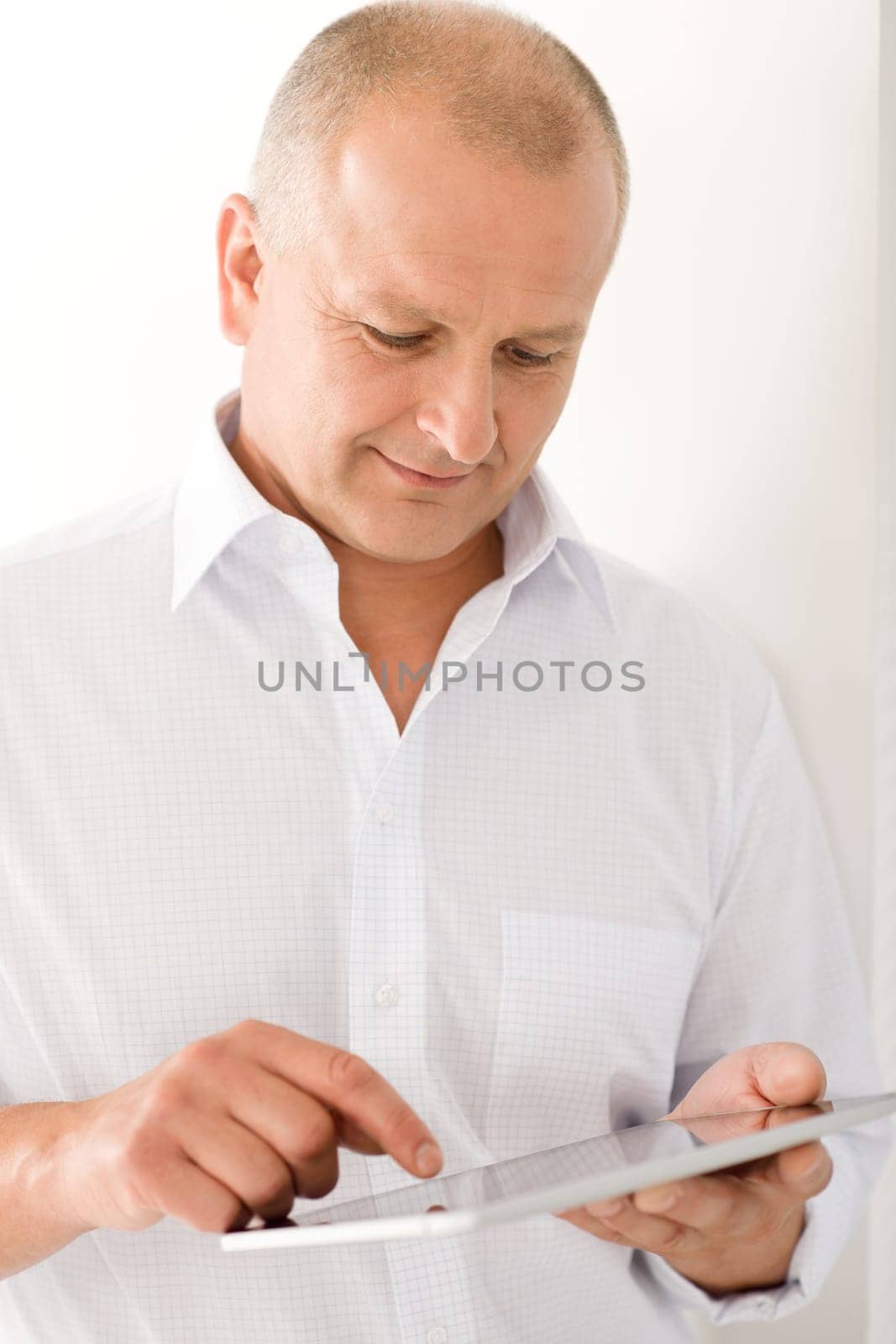 Handsome mature businessman holding look down touch tablet screen computer