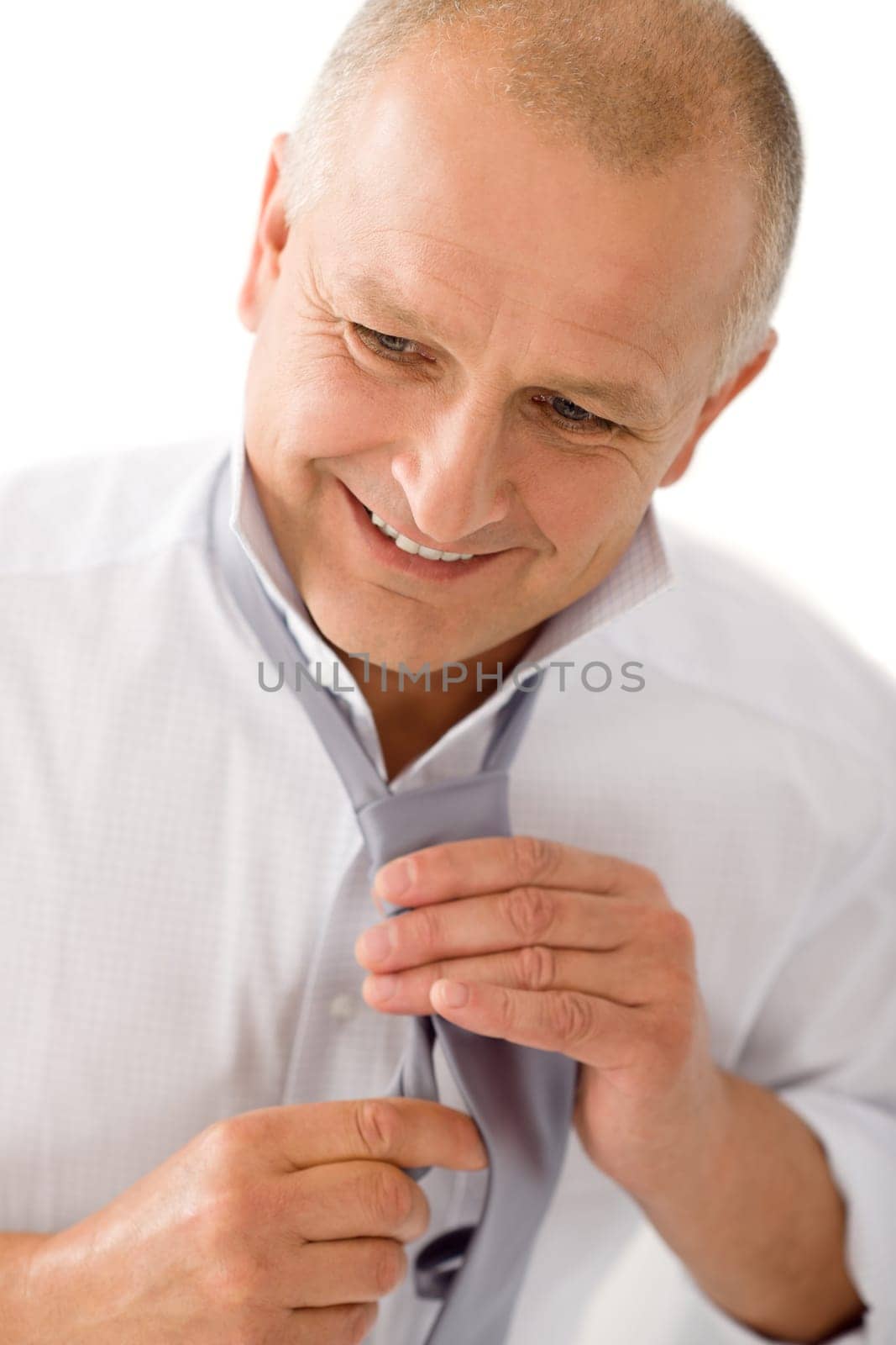 Handsome stylish mature business man smiling tie a tie closeup