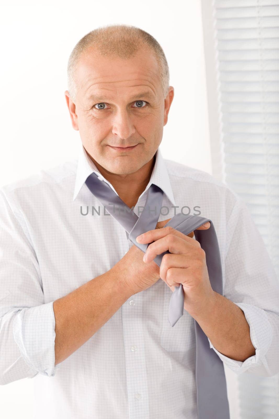 Handsome stylish mature business man tie a tie white shirt