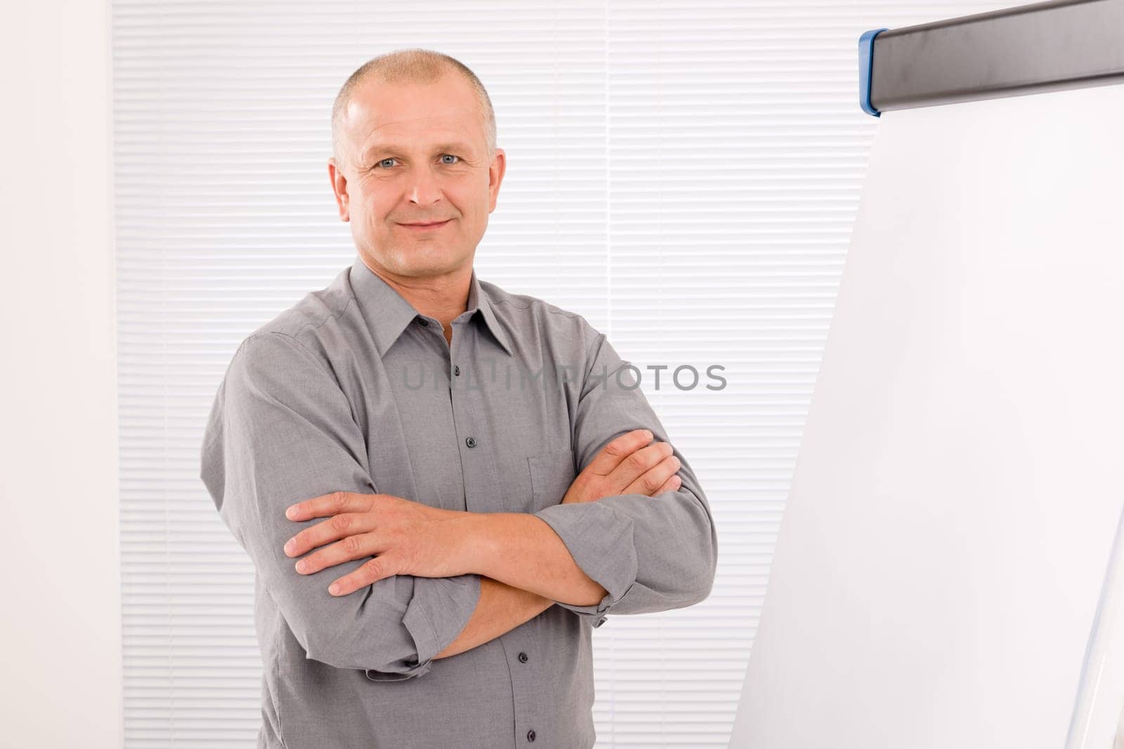 Mature handsome businessman standing in front of empty flip chart