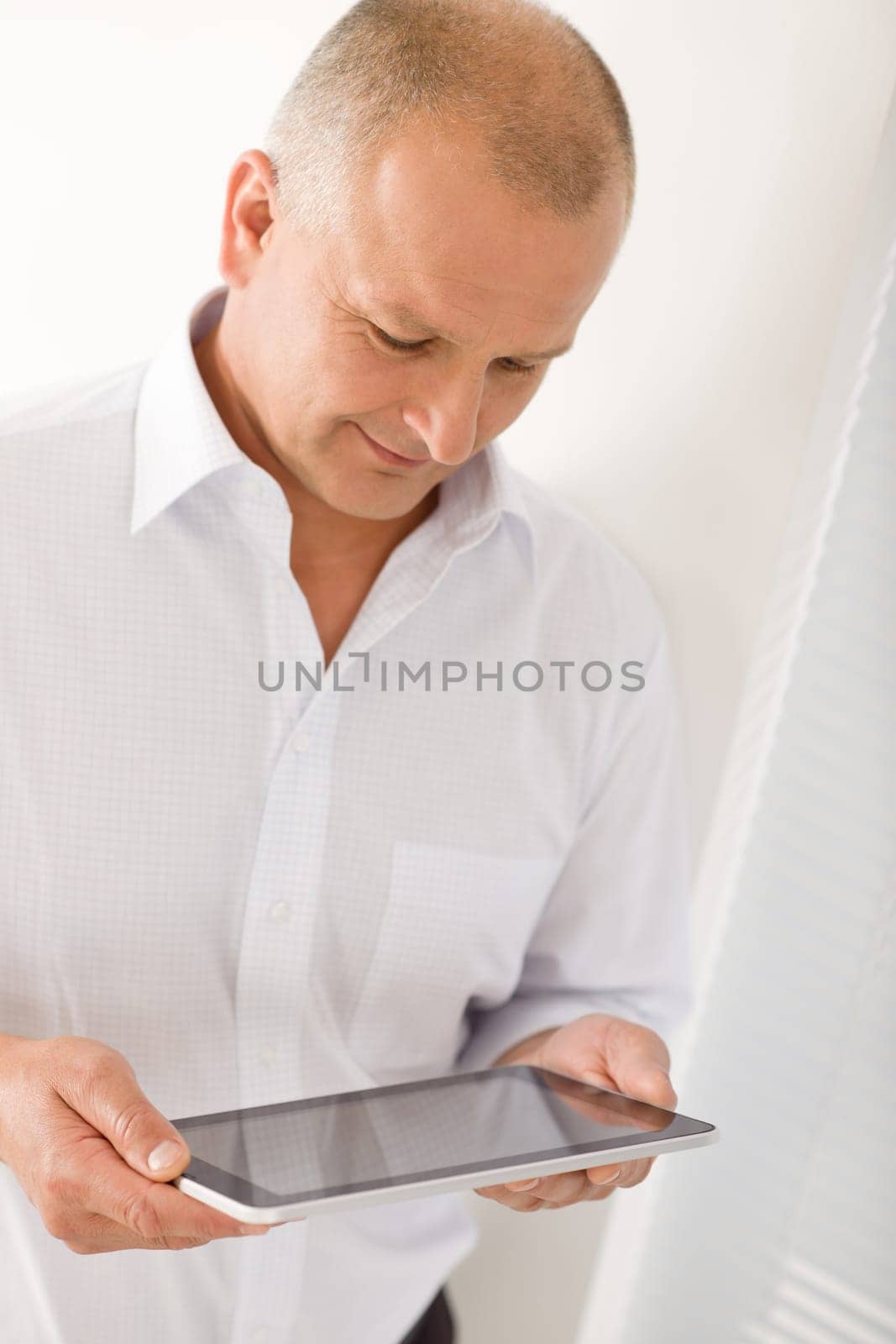 Handsome mature businessman holding look down touch tablet screen computer