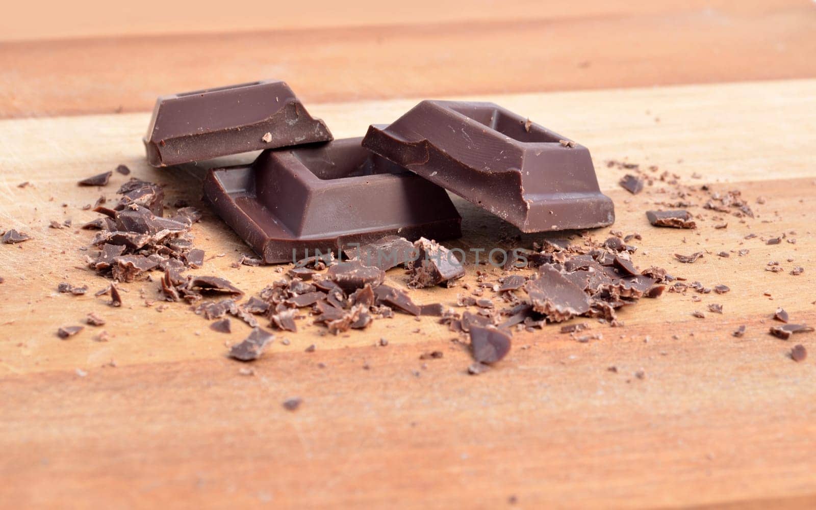 Chocolate squares and crumbles on wood surface