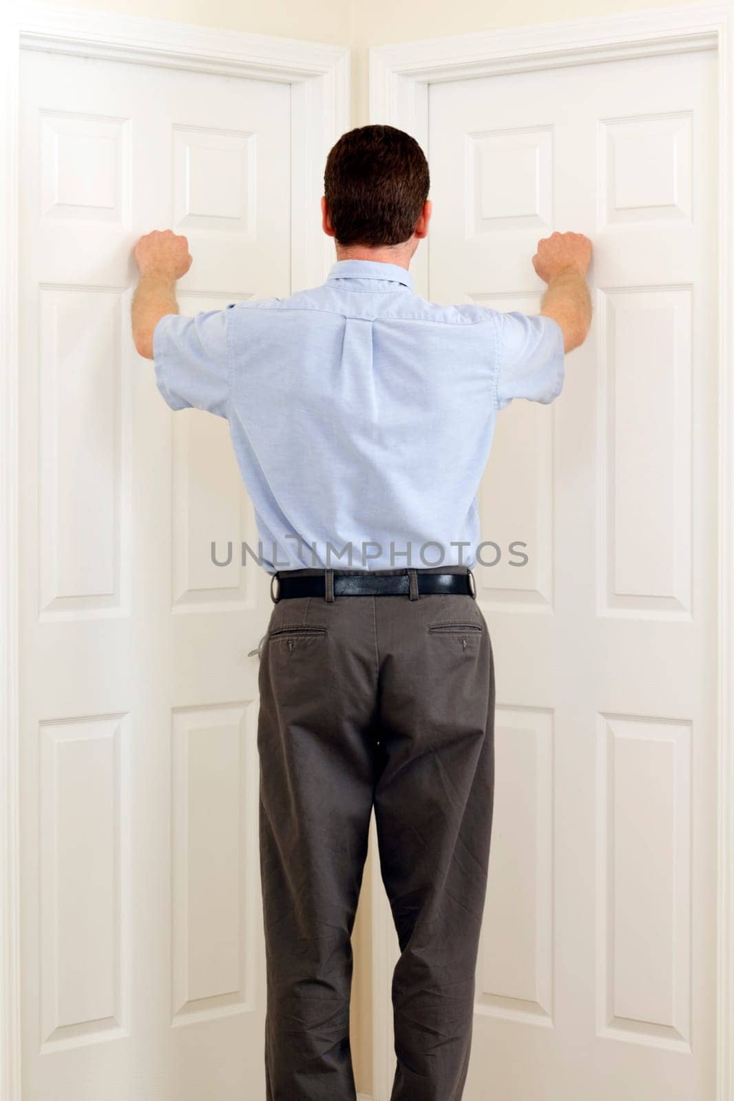 Man knocking on two doors that are side by side at the same time.