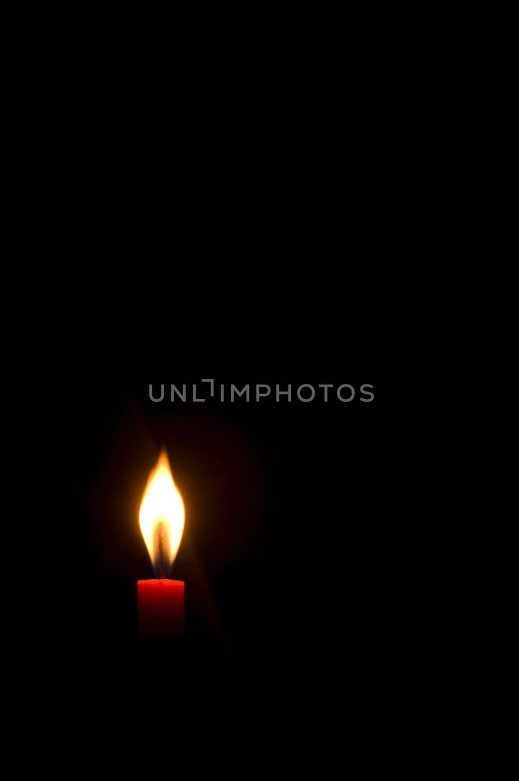 a burning candle in darkness, with copy space.