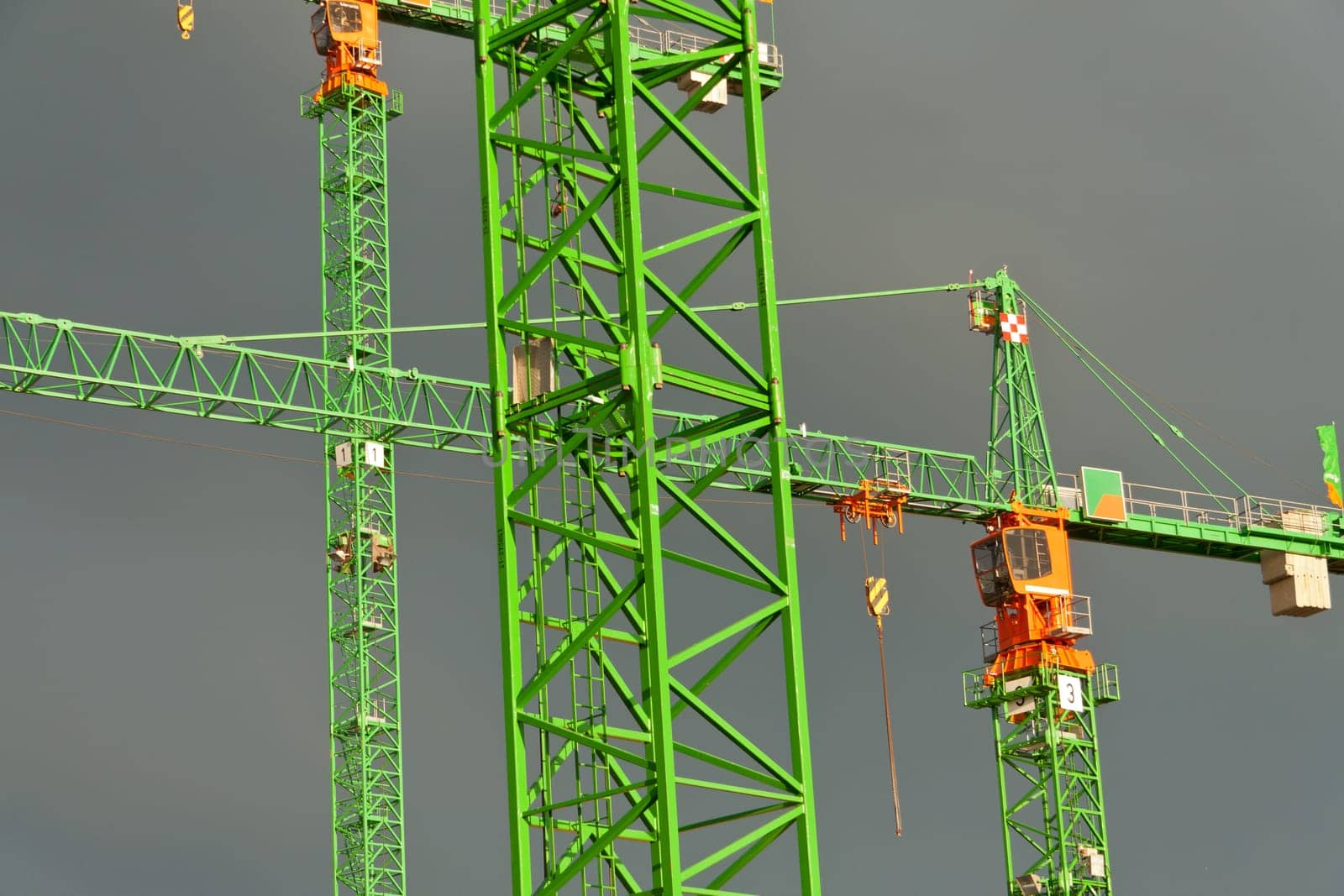 Construction cranes struck by the sun in front of dark clouds