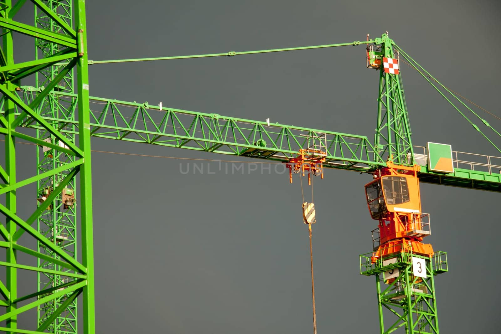 Construction cranes struck by the sun in front of dark clouds