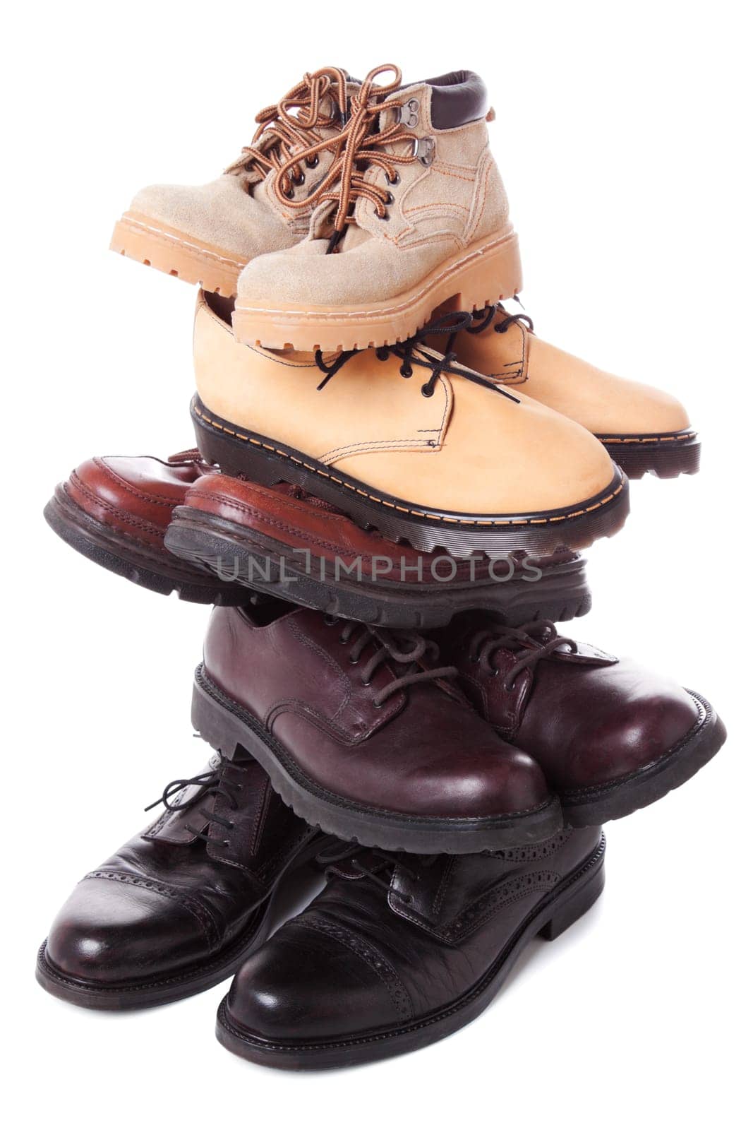 Stack of male leather boots isolated over white background