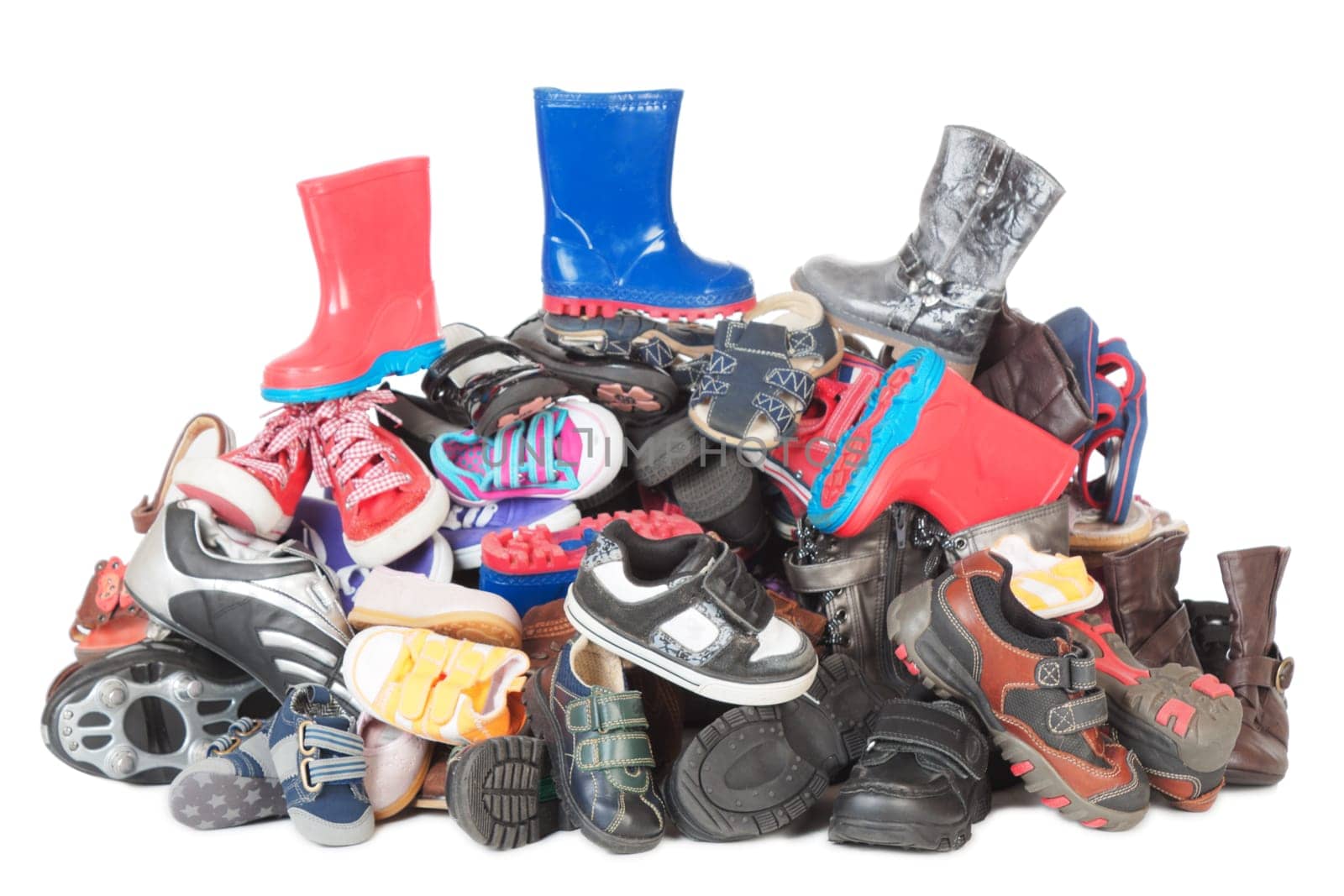 Colorful heap of old child boots and shoes isolated over white background
