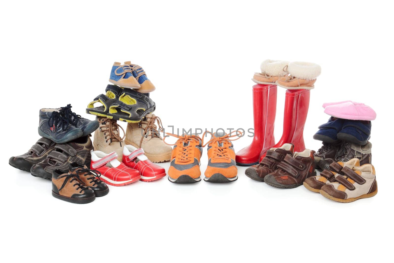 Large group of child footwear isolated over white background. Shoes organised in stacks and symmetrical line.