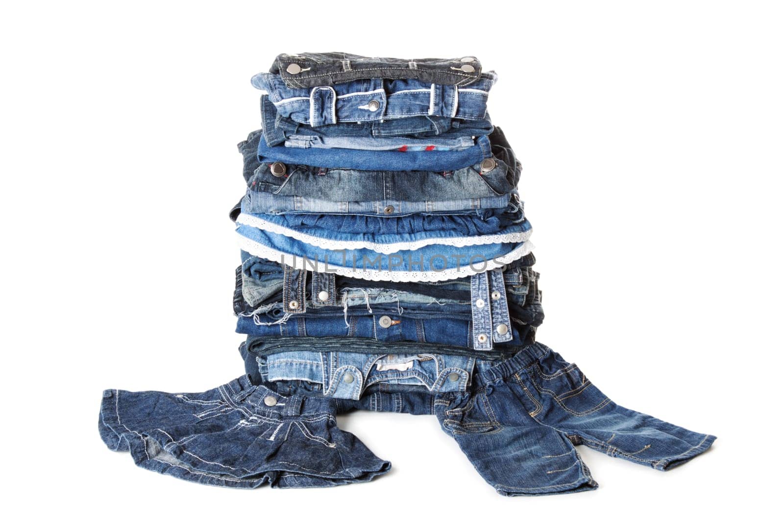 Blue pile of jeans clothes. Also skirt for little girl and pants of a boy. Isolated over white background