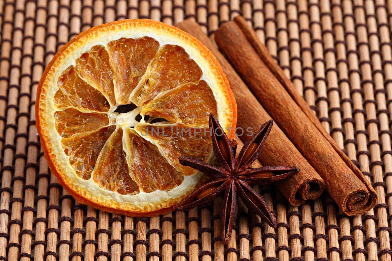 Orange slice,anime sticks and cinnamon sticks on bamboo mat.