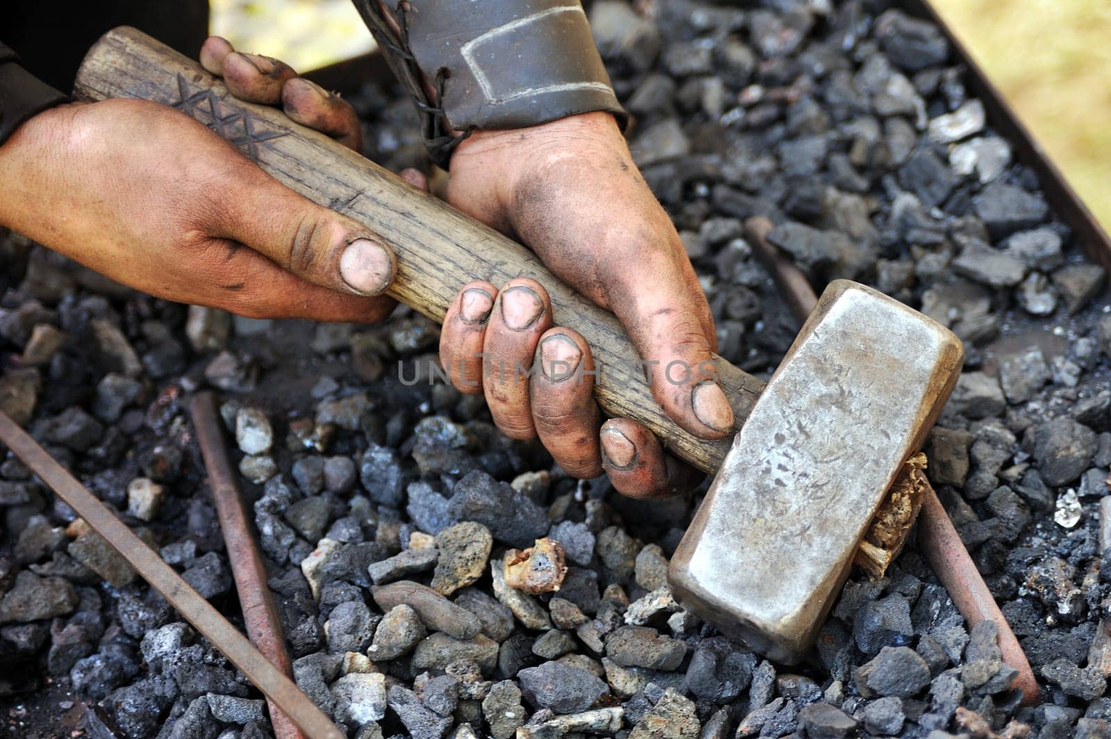 Detail of dirty hands holding hammer - blacksmith