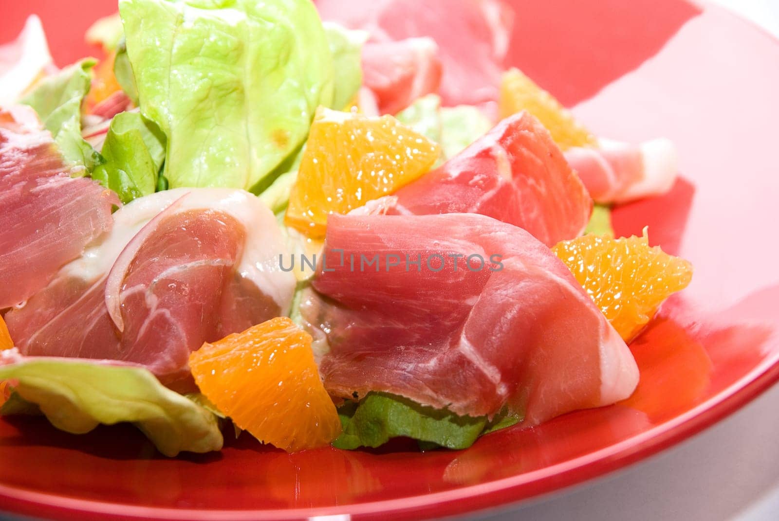 Close up of jamon salad at red dish on white
