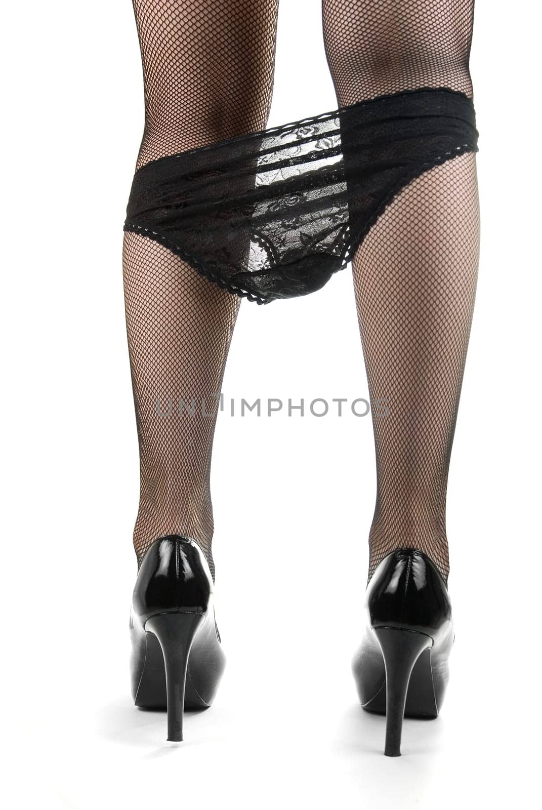 Back view of female legs with black panties, black stockings and in black shoes