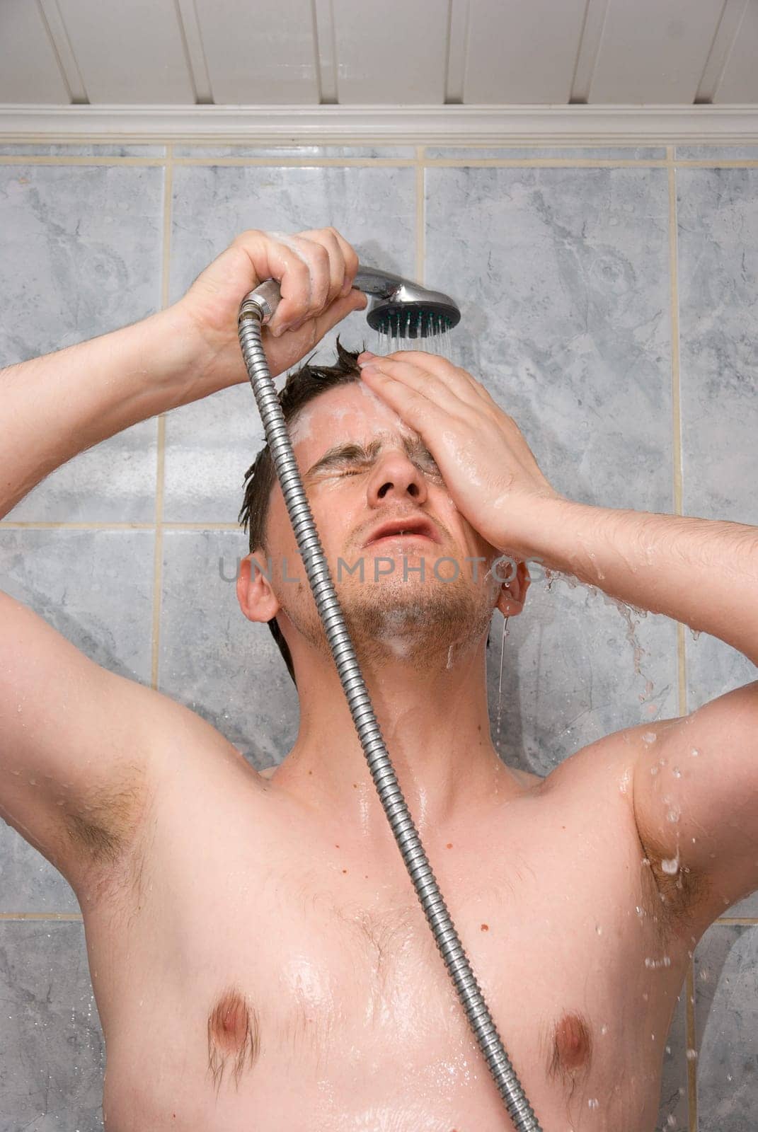 Man having shower in bathroom with soap and shampoo