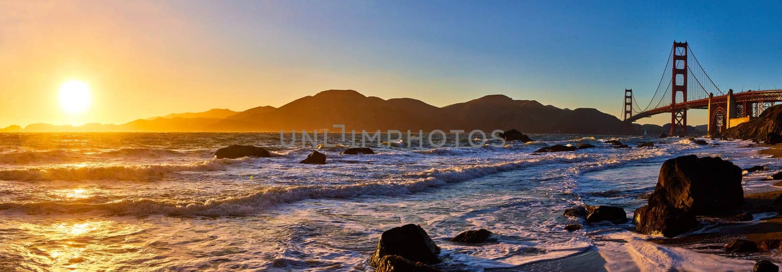 Panorama sunset over waves and distant mountain with Golden Gate Bridge by njproductions