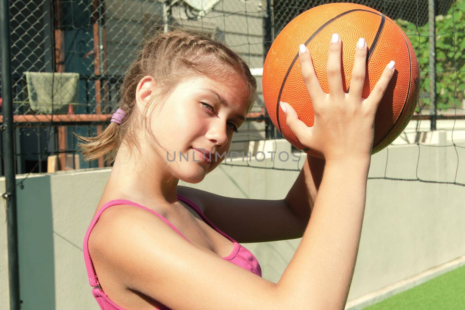 Attractive teenage girl is holding a basketball in her hands.