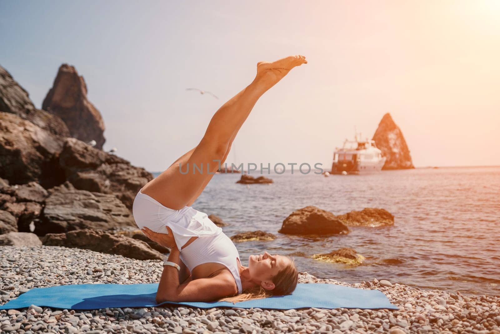 Woman sea yoga. Two happy women practicing yoga on the beach with ocean and rock mountains. Motivation and inspirational fit and exercising. Healthy lifestyle outdoors in nature, fitness concept. by panophotograph