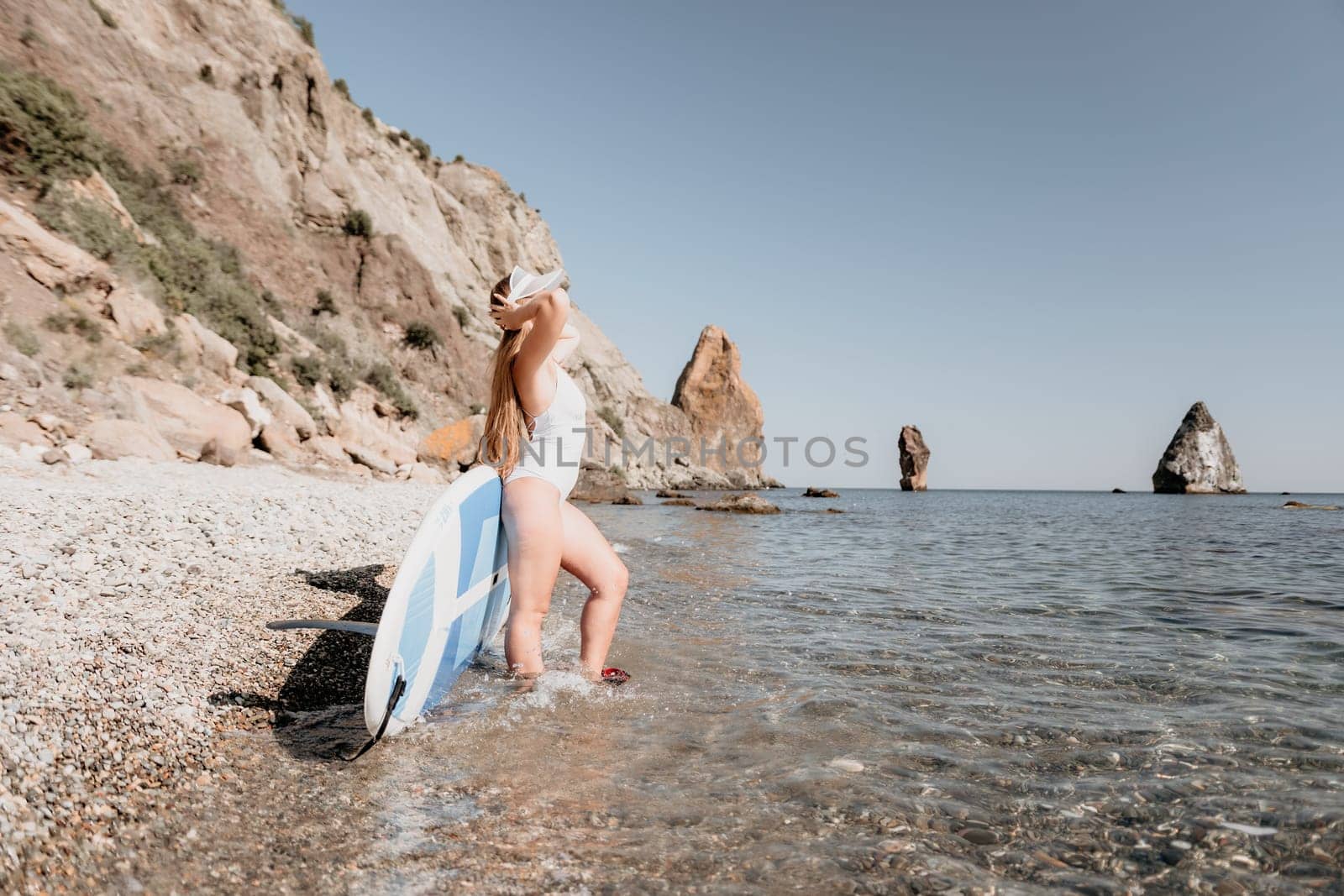 Close up shot of happy young caucasian woman looking at camera and smiling. Cute woman portrait in bikini posing on a volcanic rock high above the sea