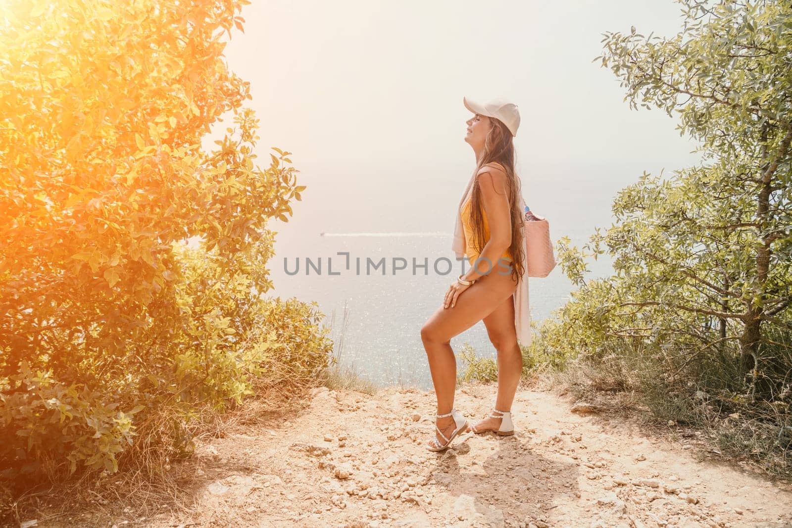 Woman travel sea. Happy tourist taking picture outdoors for memories. Woman traveler looks at the edge of the cliff on the sea bay of mountains, sharing travel adventure journey.