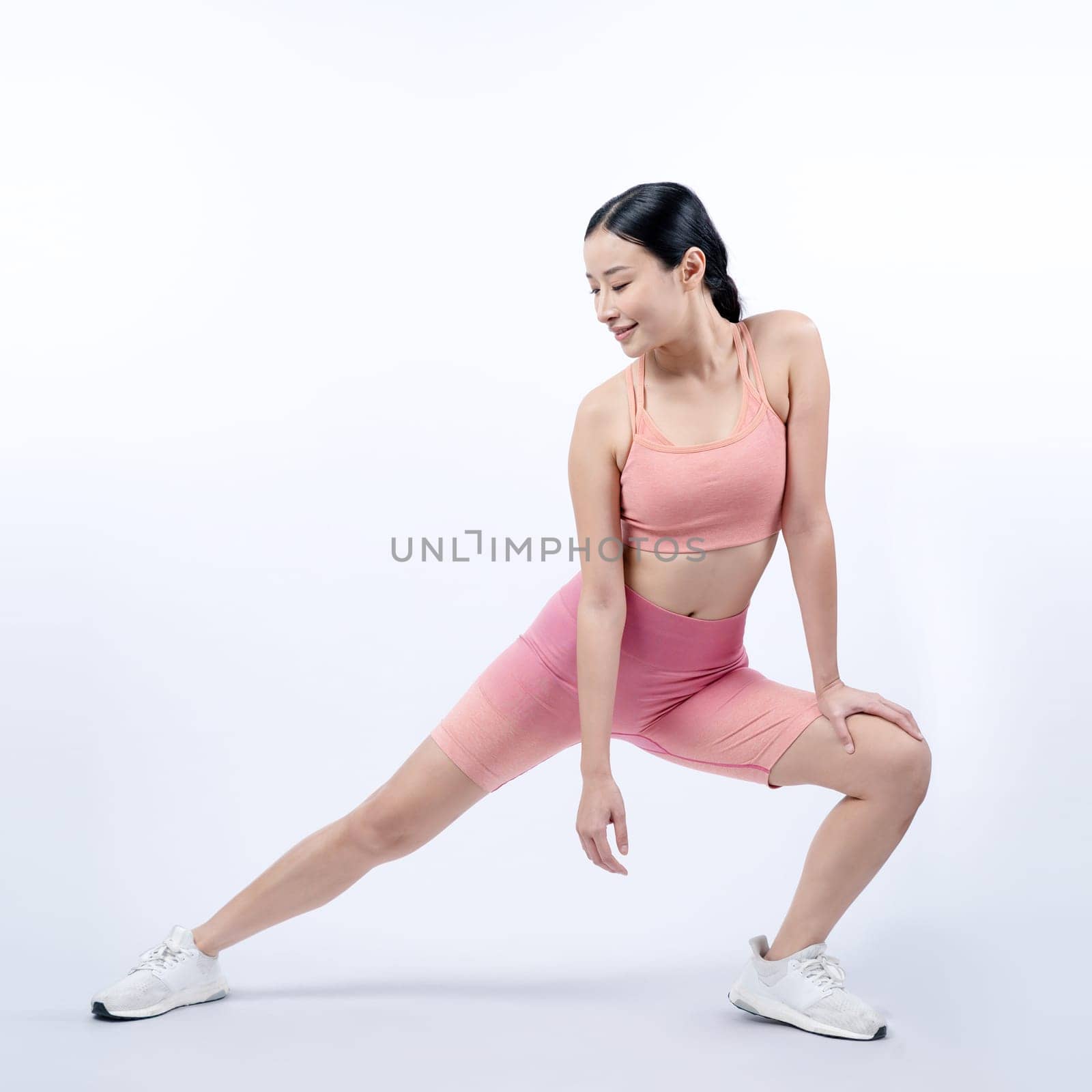 Young attractive asian woman in sportswear stretching before fitness exercise routine. Healthy body care workout with athletic woman warming up on studio shot isolated background. Vigorous