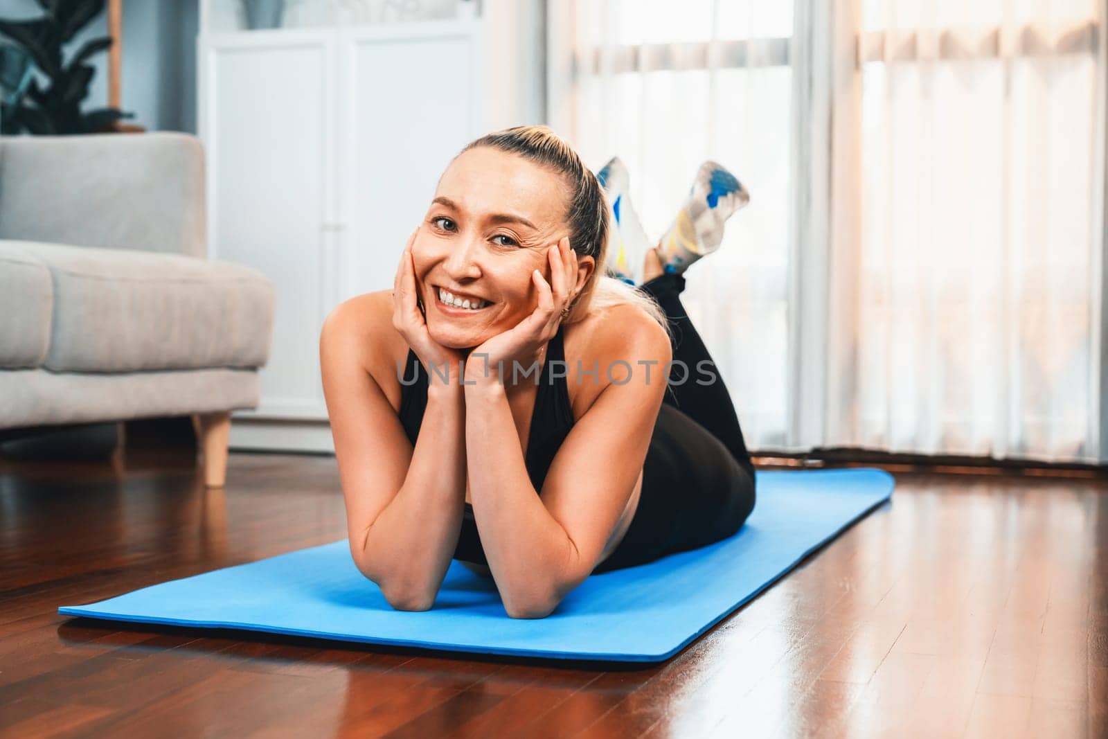 Senior woman in sportswear portrait being doing yoga on exercising mat at home. Healthy senior pensioner lifestyle with peaceful mind and serenity. Clout