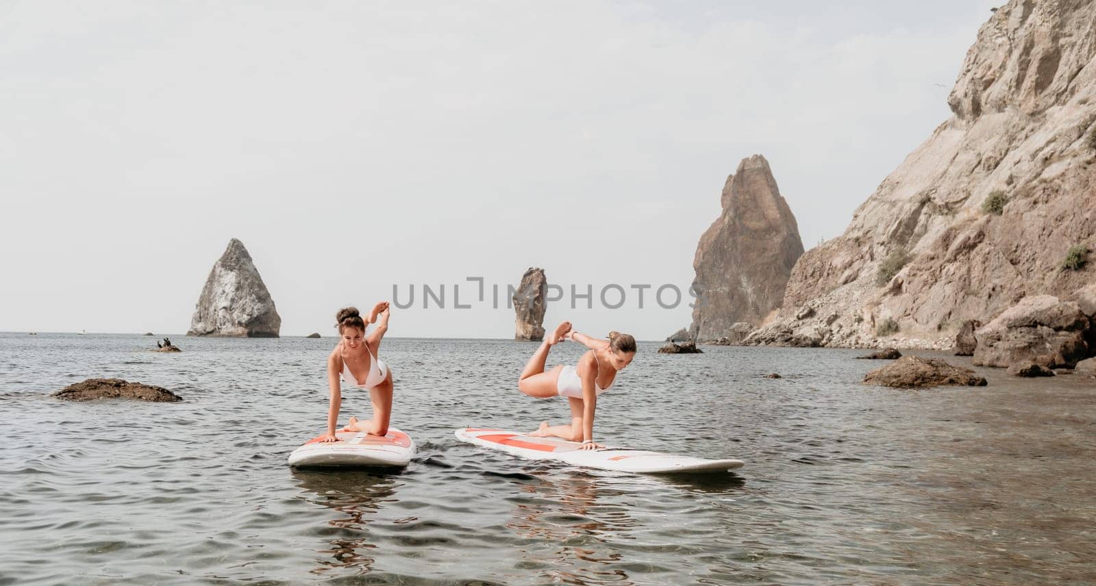 Woman sup yoga. Middle age sporty woman practising yoga pilates on paddle sup surfboard. Female stretching doing workout on sea water. Modern individual hipster outdoor summer sport activity