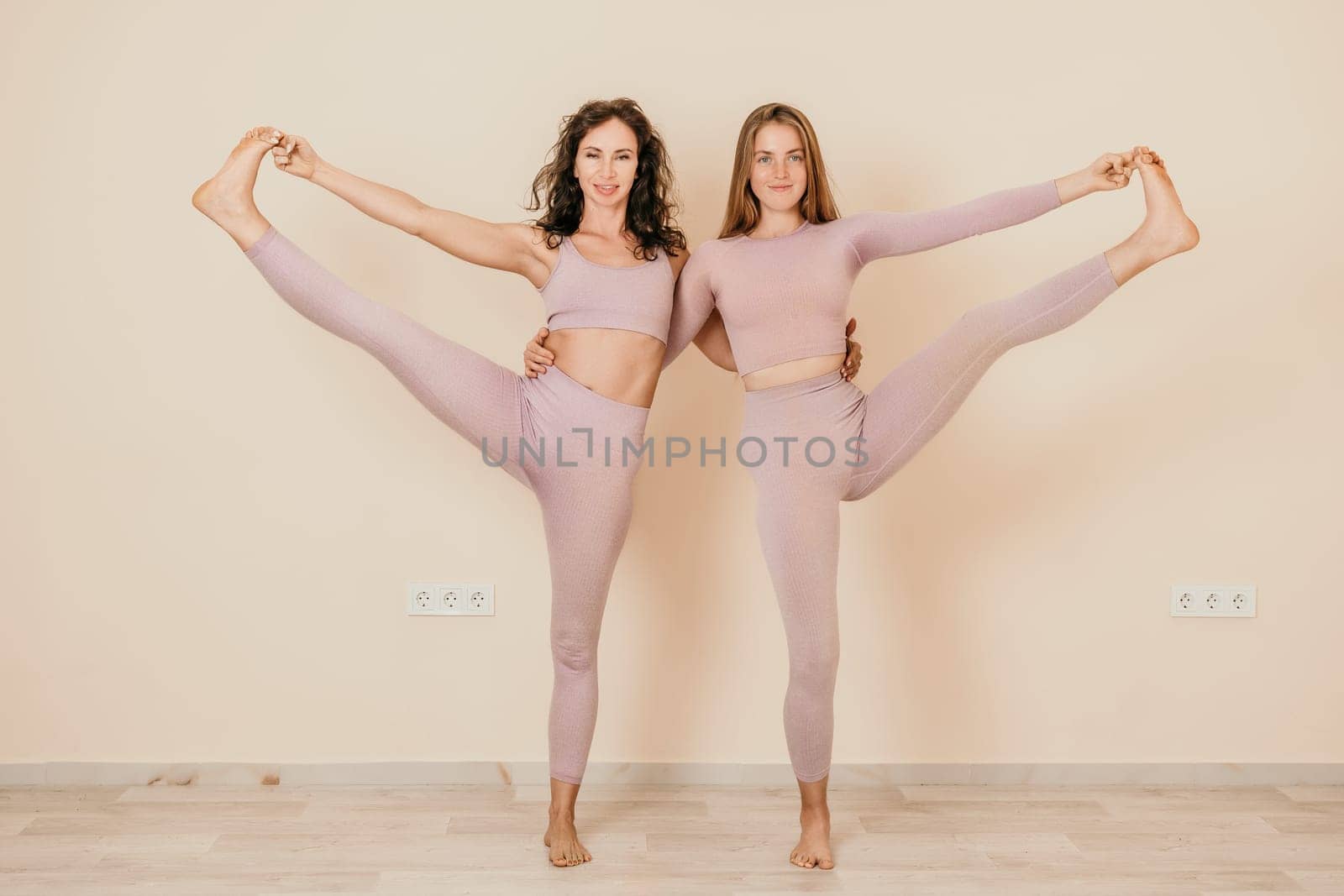 Well looking middle aged sporty woman, fitness instructor in pink sportswear doing stretching and pilates on yoga mat in the studio with mirror. Female fitness yoga. Healthy lifestyle and harmony. by panophotograph