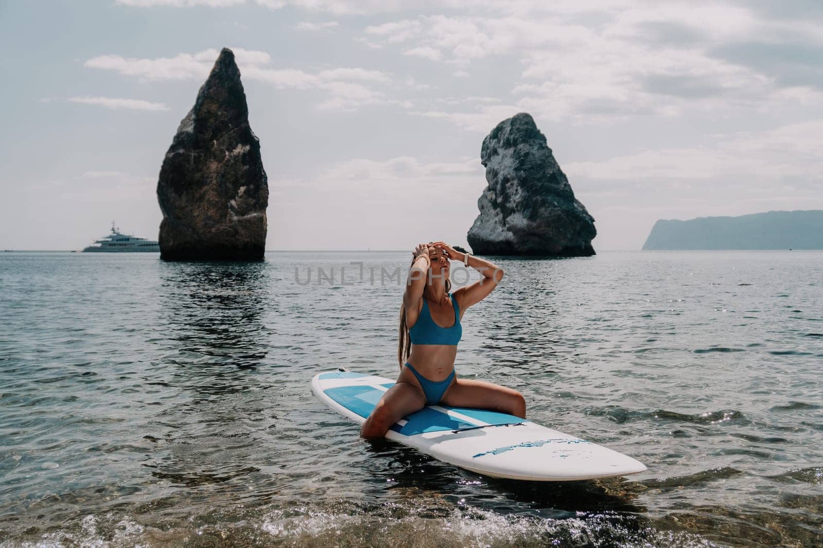 Woman sea sup. Close up portrait of happy young caucasian woman with long hair looking at camera and smiling. Cute woman portrait in bikini posing on sup board in the sea by panophotograph