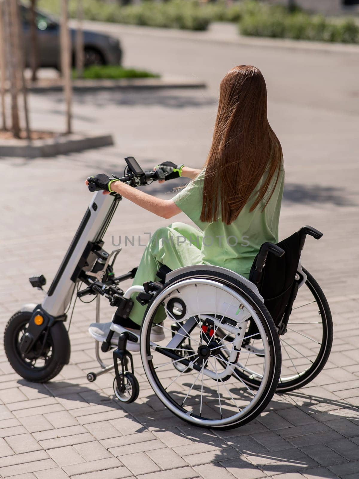 A woman in a wheelchair with an assistive device for manual control. Electric handbike