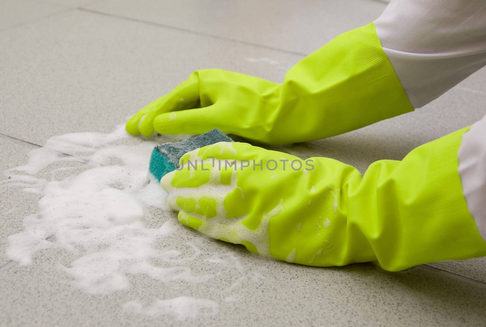 Hand in glove scrubbing tile with a sponge