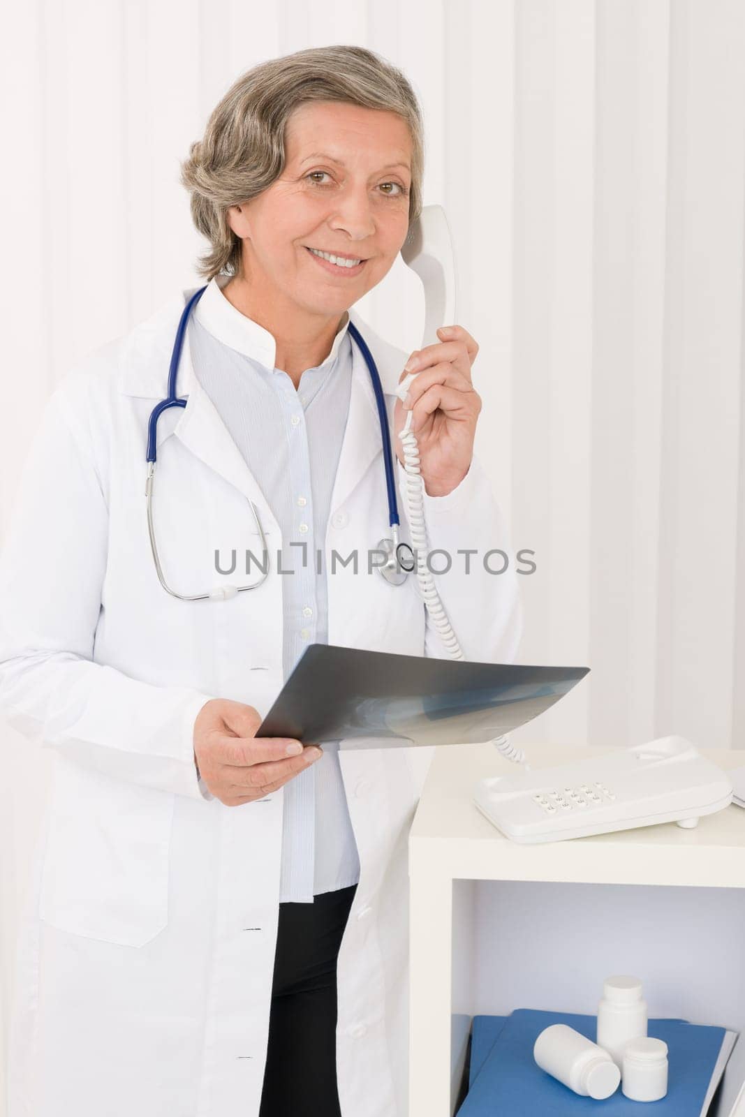 Professional senior doctor female on phone hold x-ray at office