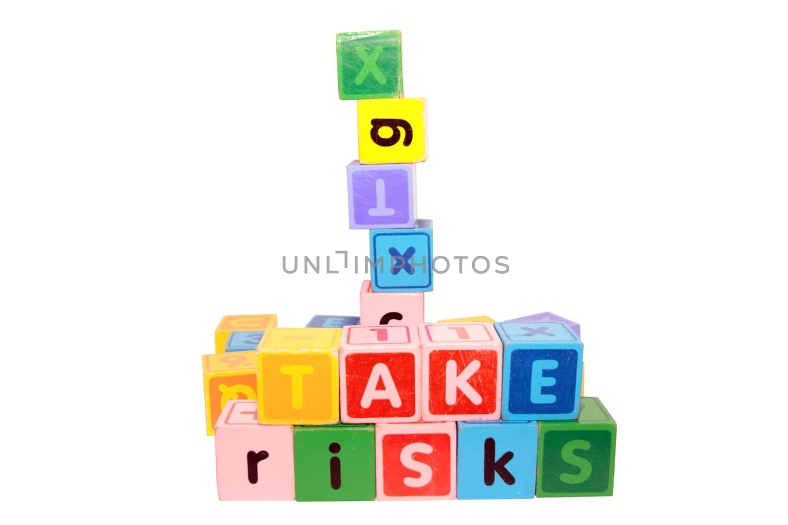 assorted childrens toy letter building blocks against a white background that spell take risks