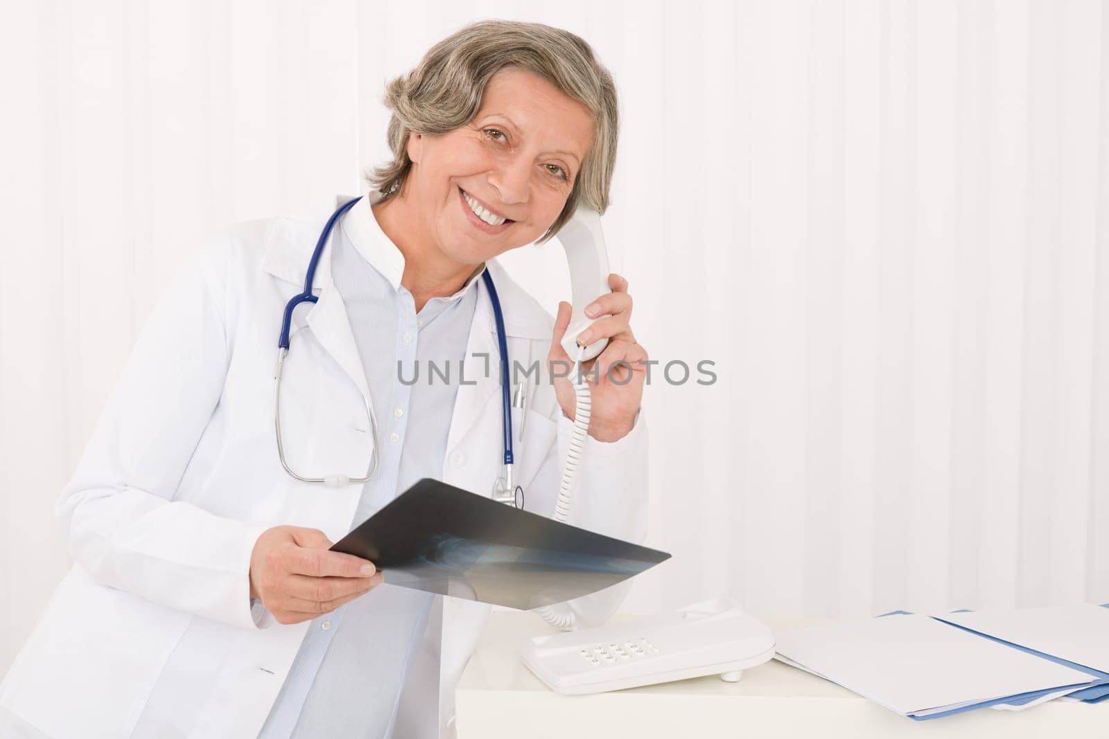 Professional senior doctor female on phone hold x-ray at office