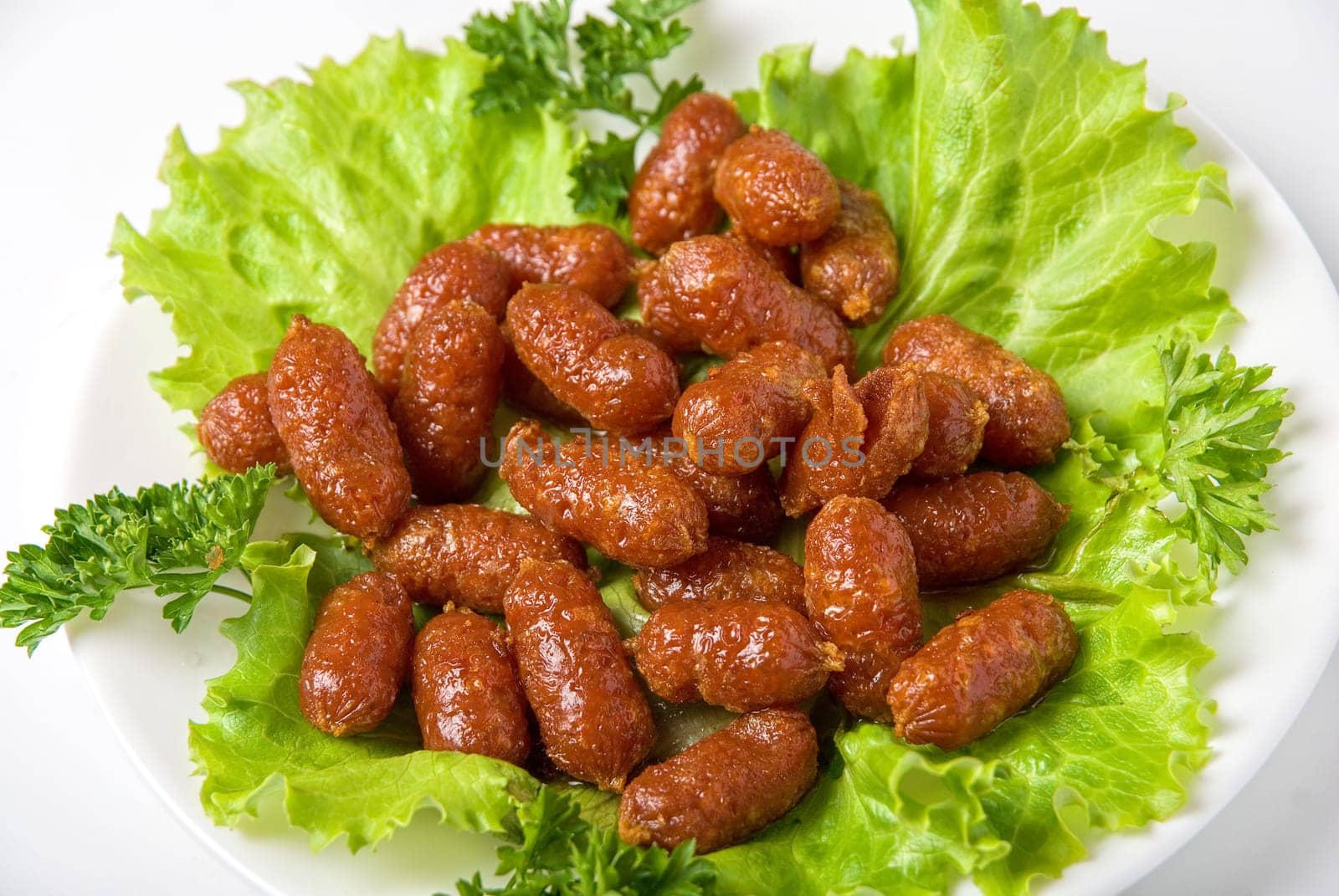 roasted tasty sausages on green lettuce with isolated on white