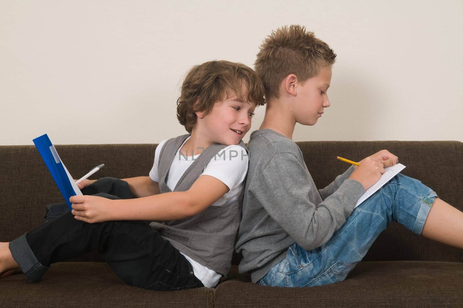 Two friends doing their homework in the livingroom on the couch