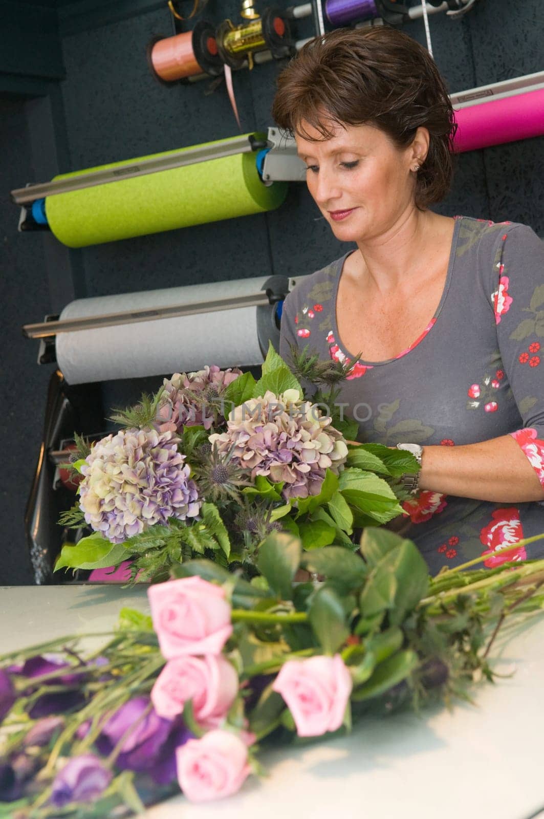 Female florist working in a flower store, making the bouquet ready for the customer