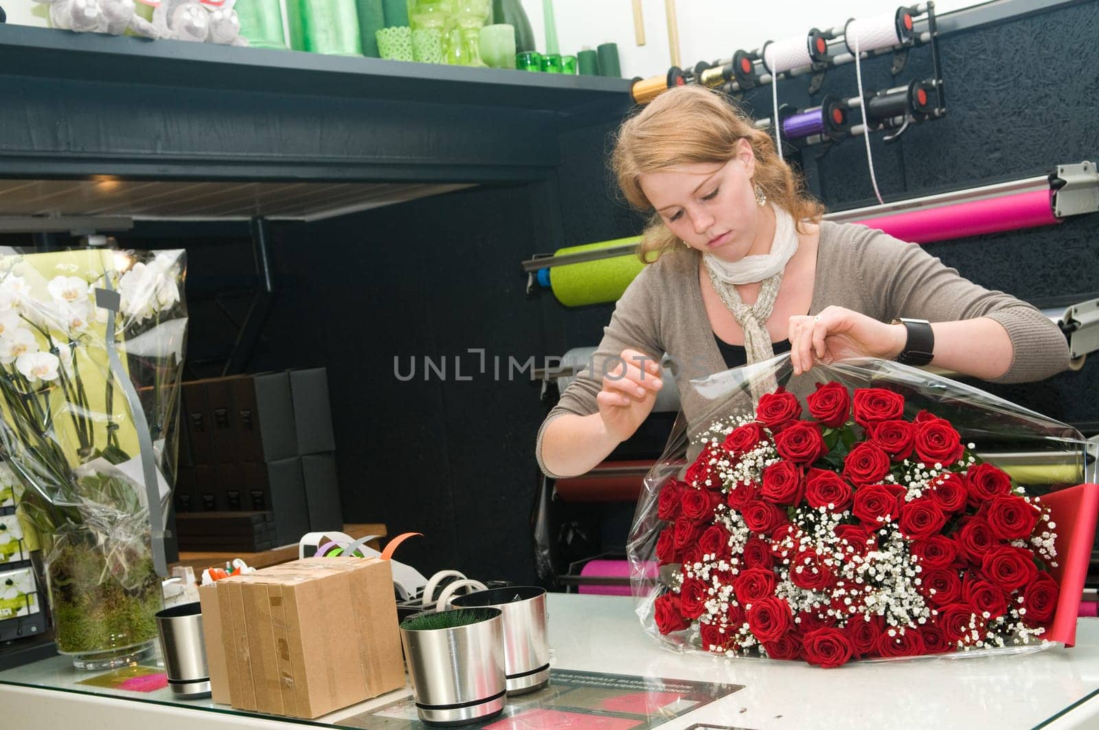 Female florist working in a flower store, making the bouquet ready for the customer