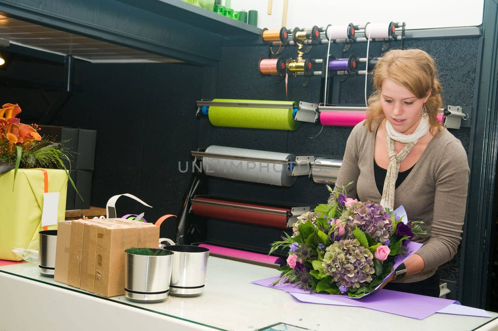 Female florist working in a flower store, making the bouquet ready for the customer